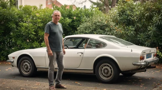Propriétaire contemplant sa voiture de collection vintage garée dans allée résidentielle